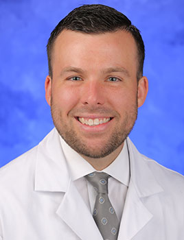 Photo of Christopher Weller, MD, pictured wearing white medical coat